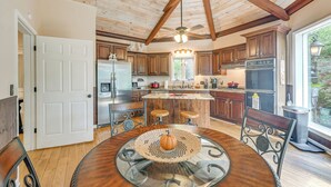 Una cocina amplia con armarios de madera, una isla central y un comedor con mesa de vidrio.