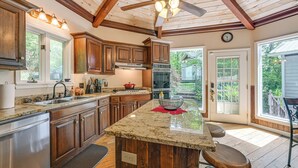 Una cocina con armarios de madera, encimeras de granito, una isla central y un ventilador de techo.