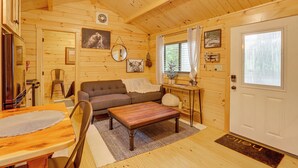 A wooden cabin interior with a dining area, sofa, and a door with a window.