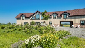 A large, modern building with a spacious driveway and outdoor seating area. - Grill Out, Play Pool: Huge Home on Lake Champlain! (Chazy)