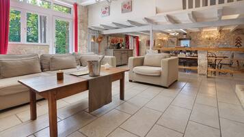 Een ruime woonkamer met een houten salontafel, beige banken en een keuken op de achtergrond.
