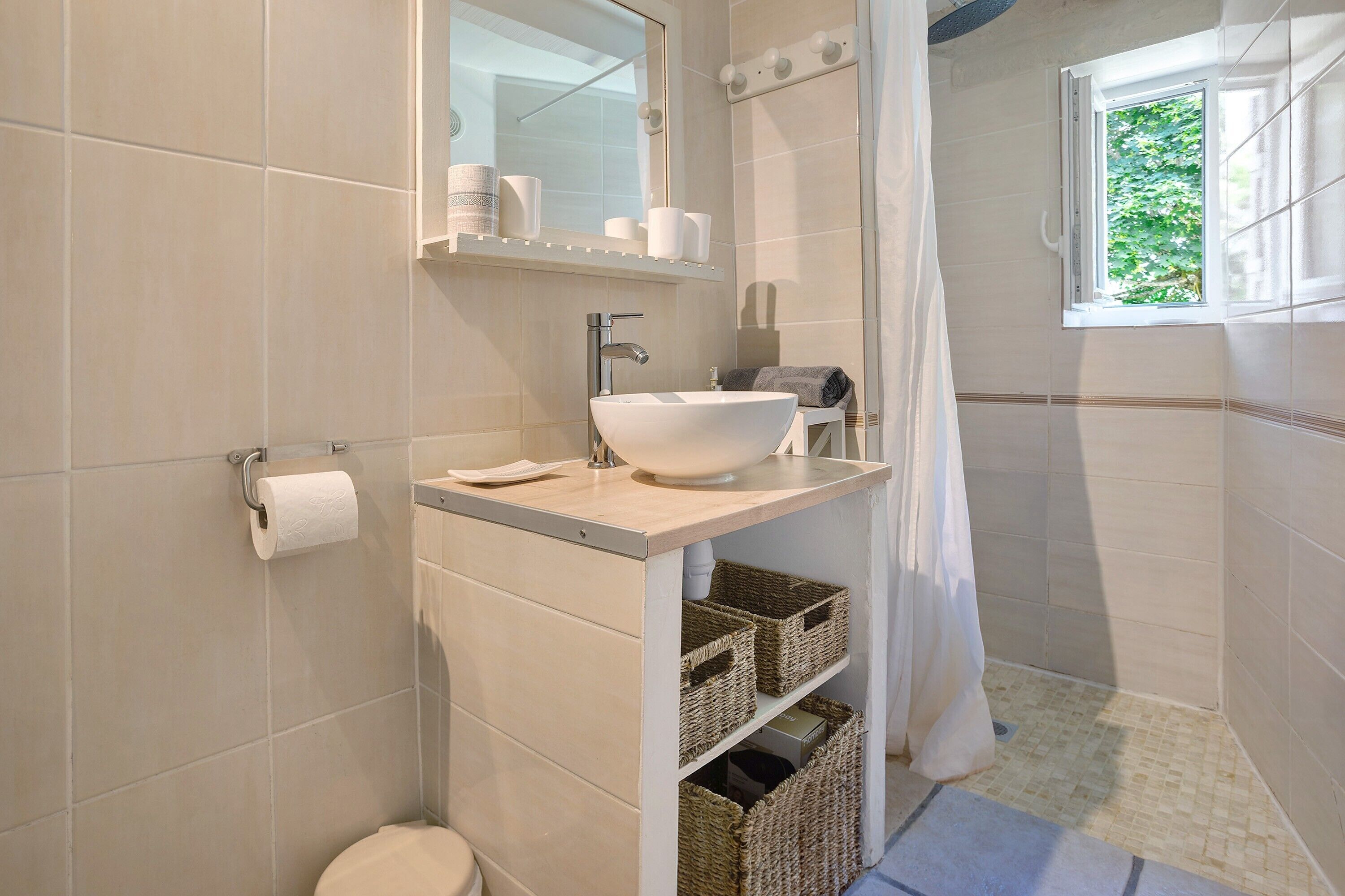 Ein Badezimmer mit Waschbecken, Spiegel, Toilette und Fenster.