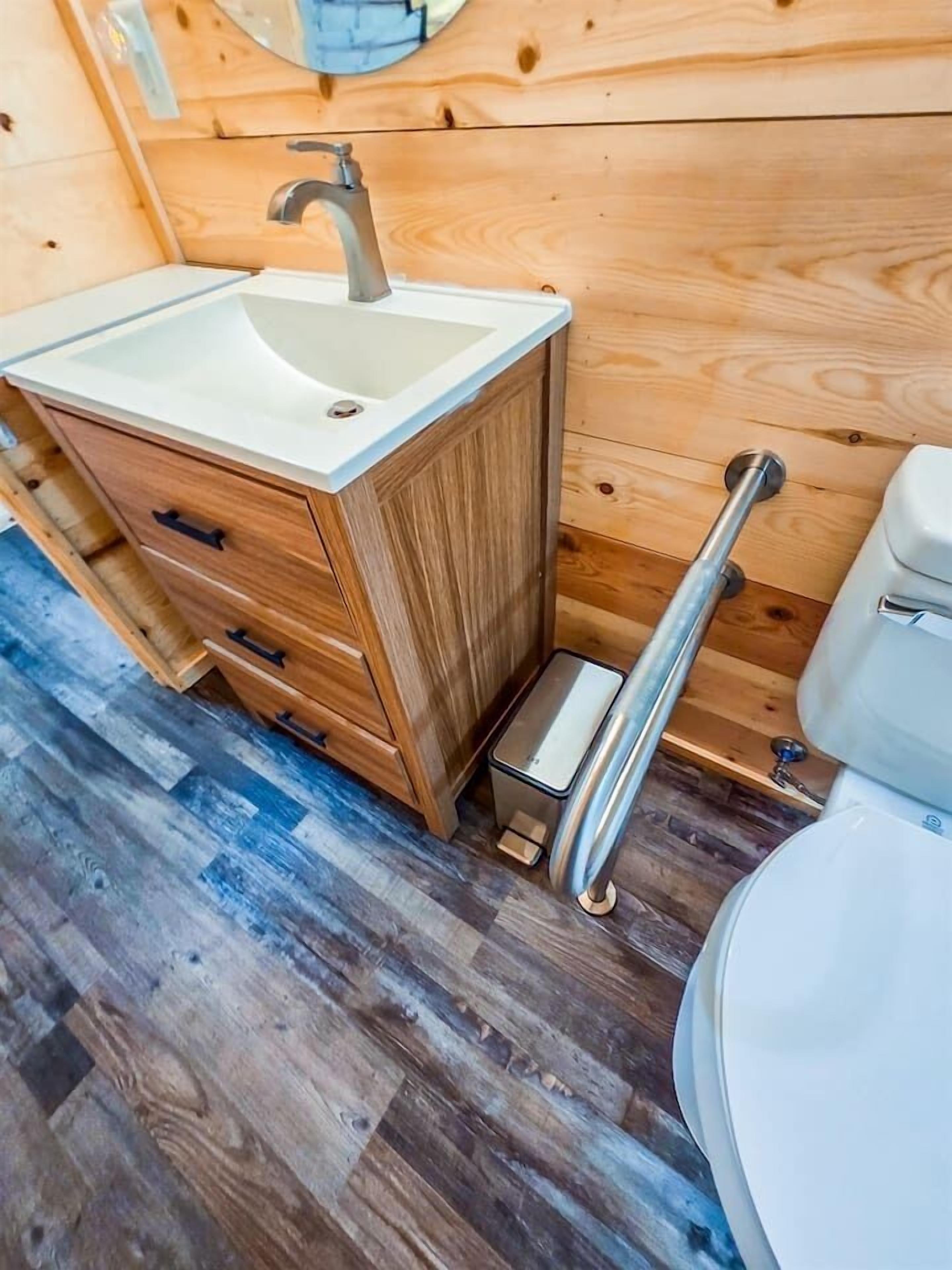 Ein Badezimmer in einer Holzhütte mit Waschbecken, Schrank und Toilette.