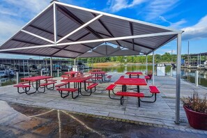 Un espacio al aire libre techado con mesas de picnic y vistas al agua.