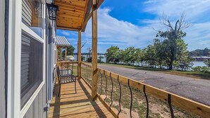A wooden deck with a railing, a bench, and a view of a lake and trees.