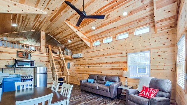 L’intérieur d’une cabane en bois comprend un coin repas, un canapé et un escalier menant à un niveau supérieur.