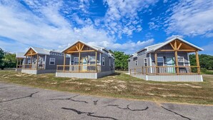 Deux petites cabanes dotées de terrasses en bois, sous un ciel d’un bleu limpide.