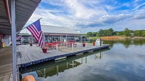 A dock with a covered seating area, an American flag, and a calm body of water.
