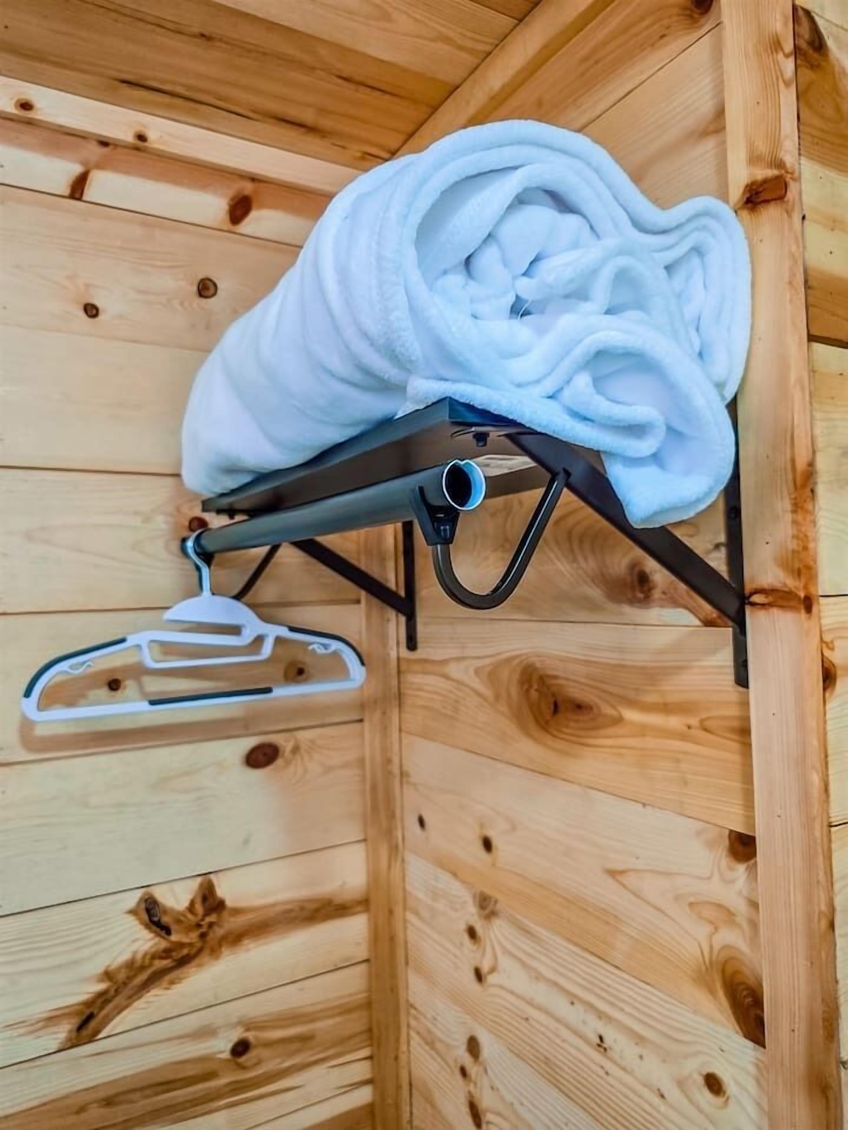 Eine Holzwand mit einem Metallregal, das ein weißes Handtuch und einen weißen Kleiderbügel trägt.