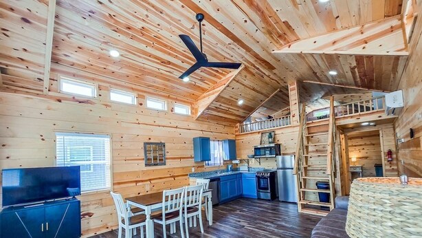 A cabin interior with a dining area, kitchen, and upper sleeping loft.