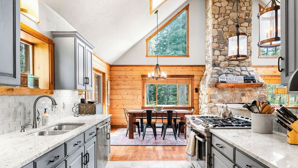 Une cuisine dotée de plans de travail en granit, d’une cheminée en pierre et d’éléments décoratifs en bois.