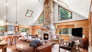 Un salon spacieux avec une cheminée en pierre, des meubles en bois et de grandes fenêtres.