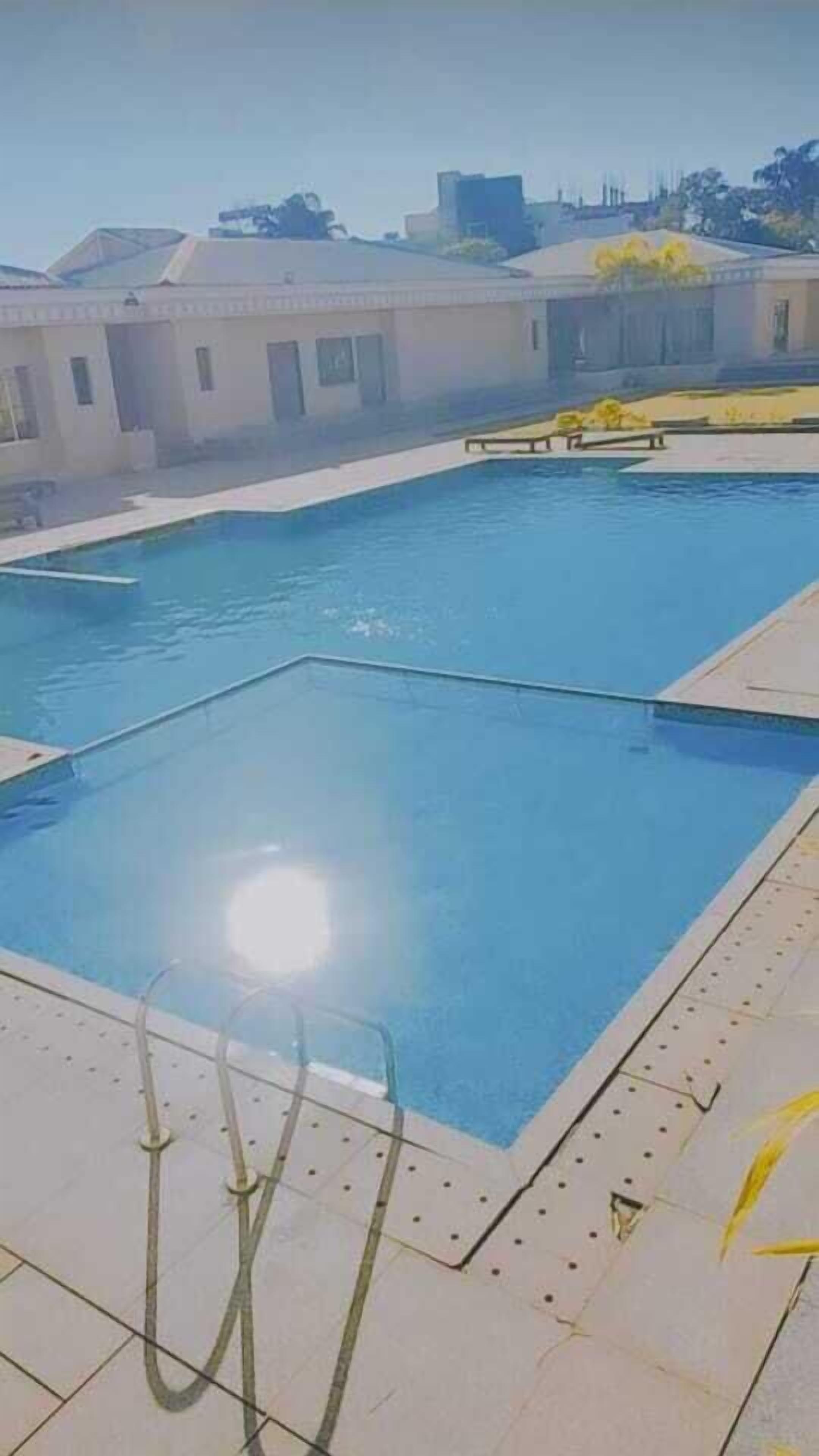 Una piscina con agua azul cristalina, rodeada por un solado de azulejos.