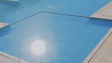 Una piscina con agua azul cristalina, rodeada por un solado de azulejos.