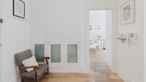 A hallway with a wooden bench, a white door with frosted glass panels, and a view into a dining area.