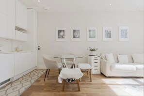 A modern, minimalist living space with a dining area, a sofa, and a kitchen.