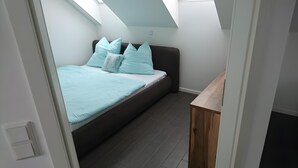 Une chambre à coucher de taille réduite, avec un lit, des oreillers et une petite table en bois.
