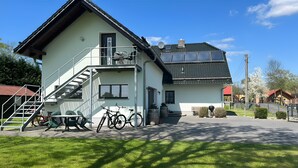 Un bâtiment à deux étages avec un escalier, un vélo et un barbecue dans la cour.