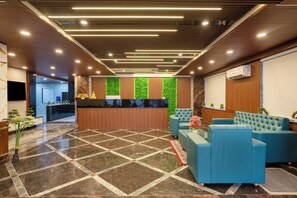 Un área de recepción con un mostrador de madera, una pared verde y sofás azules.