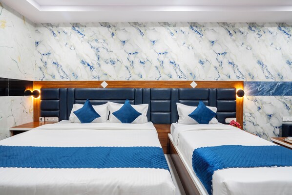 A hotel room with two beds, marble-patterned walls, and a modern headboard. - Hotel Sunrise (Hyderabad)