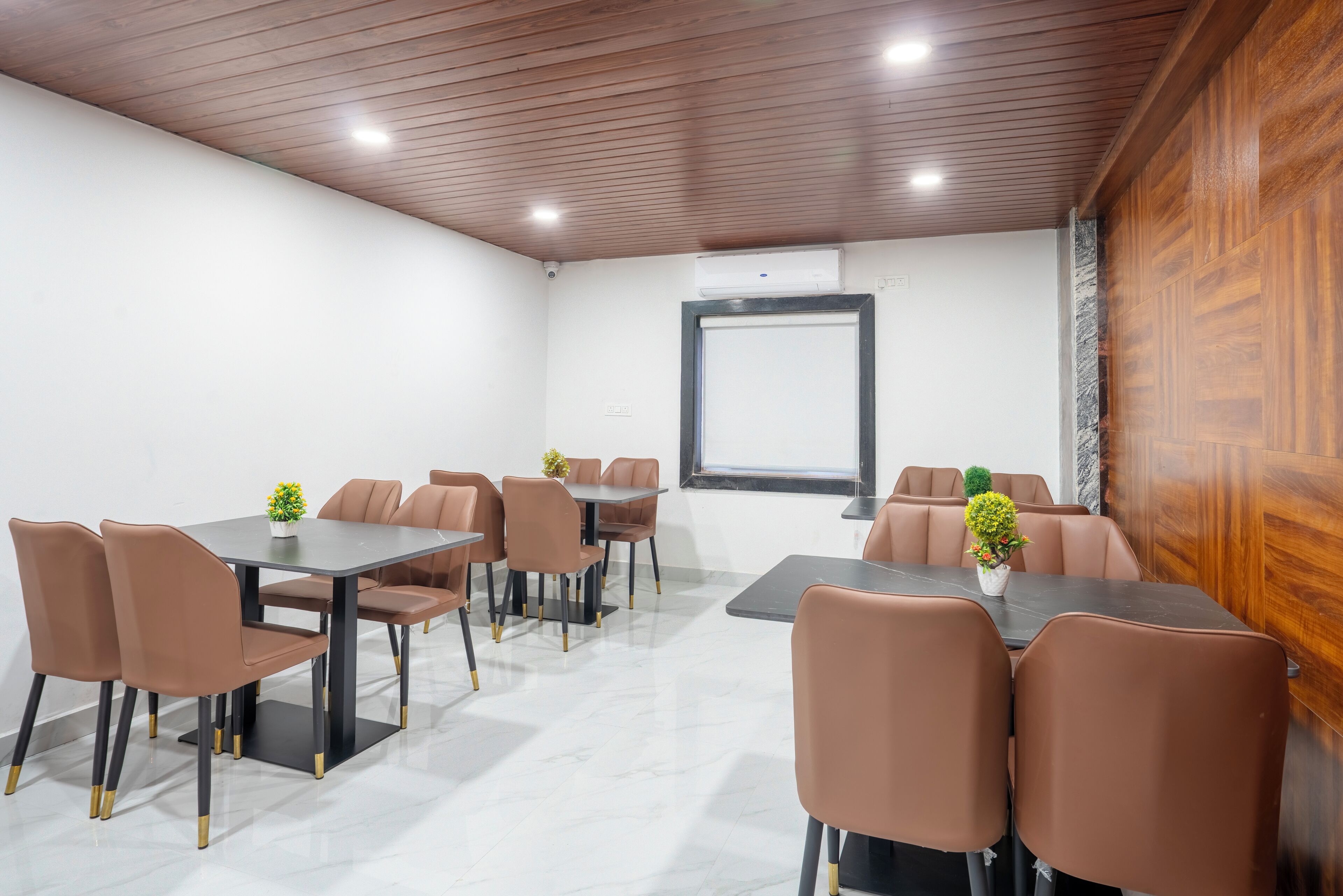 Une salle de conférence avec un plafond en bois, des murs blancs et une grande fenêtre.