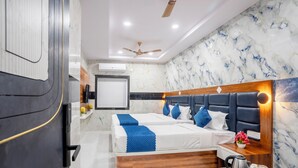 Une chambre d’hôtel moderne avec un grand lit, une table de chevet en bois et un ventilateur de plafond.