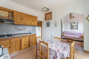 A kitchen with wooden cabinets, a tiled backsplash, a dining table with chairs, and a living area with a sofa and a wall-mounted TV. - Apartment 'Apartamento Nayara D' with Sea View, Private Terrace and Wi-Fi (Valle Gran Rey)