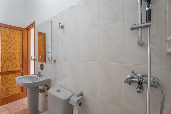 Un baño con lavamanos, inodoro, espejo y ducha.