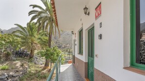 A building with a stone pathway leading to a door with a green frame. - Apartment 'Nayara A' with Sea View, Balcony and Wi-Fi (Casa de la Seda)