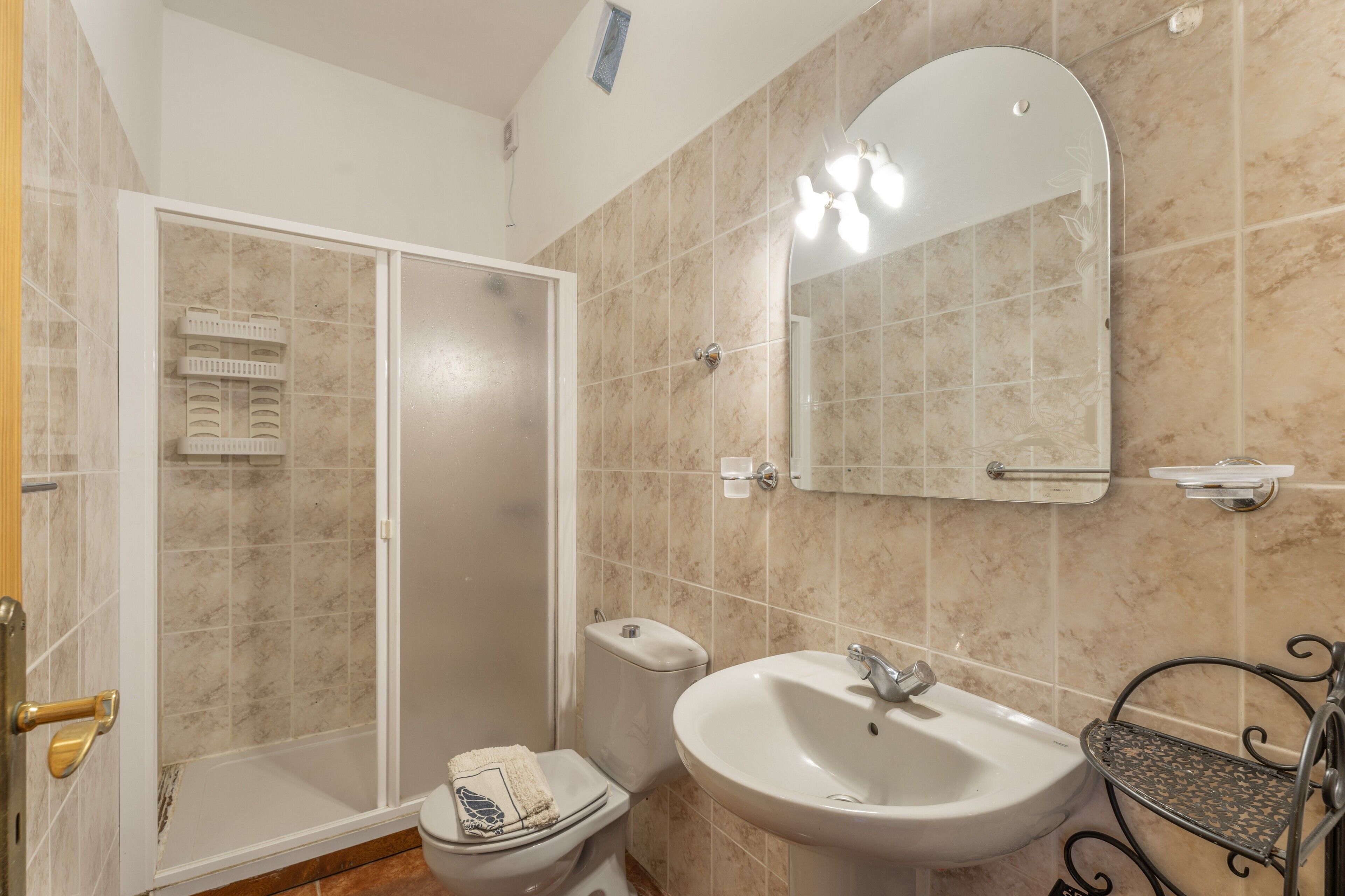 Een badkamer met douche, toilet, wastafel en een spiegel.