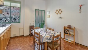 A kitchen with a dining table, chairs, a water bottle, and a bookshelf. - Apartment 'Nayara A' with Sea View, Balcony and Wi-Fi (Casa de la Seda)