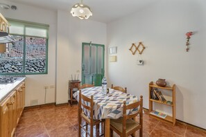 A kitchen with a dining table, chairs, a water bottle, and a bookshelf.