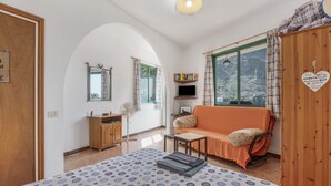 A bedroom with a bed, a wooden wardrobe, a sofa, a TV, and a window with curtains. - Apartment 'Apartamento Nayara B' with Sea View, Shared Terrace and Wi-Fi (Valle Gran Rey)