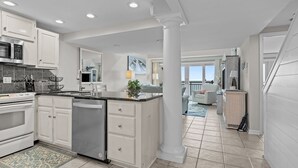 A modern kitchen with white cabinetry, stainless steel appliances, and a central island. - Beachwalk 302 - Oceanfront, 4 Bedroom, 4 Bath Condo (Pine Knoll Shores)