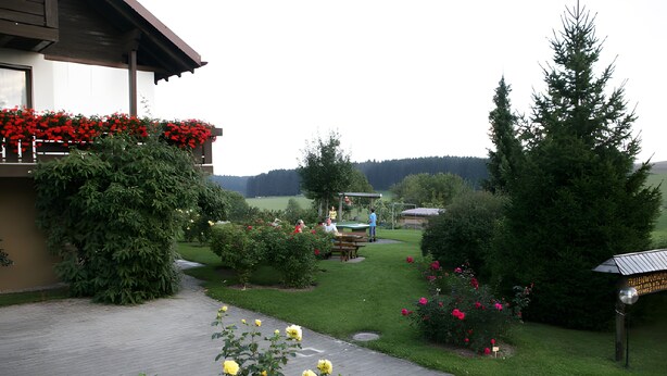 A garden with a paved walkway, a wooden building with a balcony, and a picnic table. - Apartment 'East, 48 sqm' with Shared Terrace, Shared Garden and Wi-Fi (Weilheim)