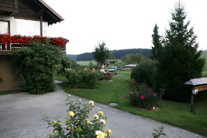 A garden with a paved walkway, a wooden building with a balcony, and a picnic table. - Apartment 'East, 48 sqm' with Shared Terrace, Shared Garden and Wi-Fi (Weilheim)