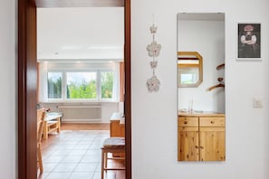 A room with a wooden cabinet, a mirror, and a window with a view of greenery.