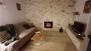 A cozy living room with a stone wall, a fireplace, a sofa, a coffee table, and a TV.