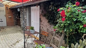 A courtyard with a red umbrella, a wooden fence, and a stone wall.