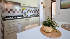 Eine moderne Küche mit Gasherd, weißen Schränken und einer Kaffeemaschine.