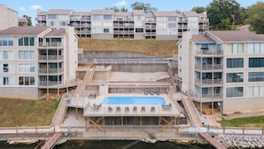 A modern apartment complex with a central swimming pool, multiple balconies, and a staircase leading to the upper floors. - Indian Pointe Lake View Pets! (Osage Beach)