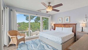 A bedroom with a large bed, a ceiling fan, a view of a lake, and a wicker chair. - Indian Pointe Lake View Pets! (Osage Beach)