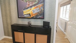 Un téléviseur fixé au mur, qui présente une texture particulière, est placé au-dessus d’une console noire dotée de panneaux perforés.