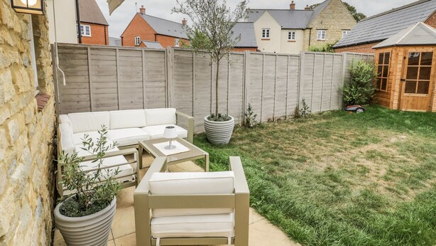 Une terrasse avec un canapé et des fauteuils, une table et des plantes en pot.