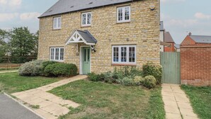 Une maison en pierre avec une porte verte, des fenêtres blanches et un petit porche.