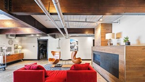 A modern hotel lobby with a red sofa, wooden reception desk, and a large painting on the wall. - Cozy 1 Bedroom with an expansive view! (Crested Butte)