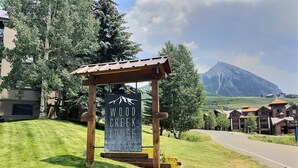 A sign for Wood Creek Lodge with a mountain view in the background. - Cozy 1 Bedroom with an expansive view! (Crested Butte)