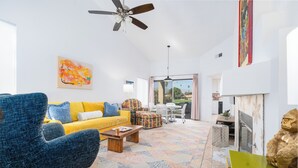 Ein geräumiges Wohnzimmer mit einem gelben Sofa, einem blauen Sessel und einem gemusterten Teppich.