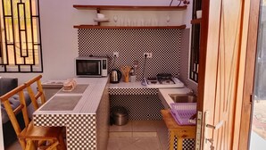 Una cocina compacta con microondas, estufa a gas y salpicadero a cuadros.