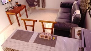 Una sala de estar con sofá, televisor, mesa de madera y una silla.